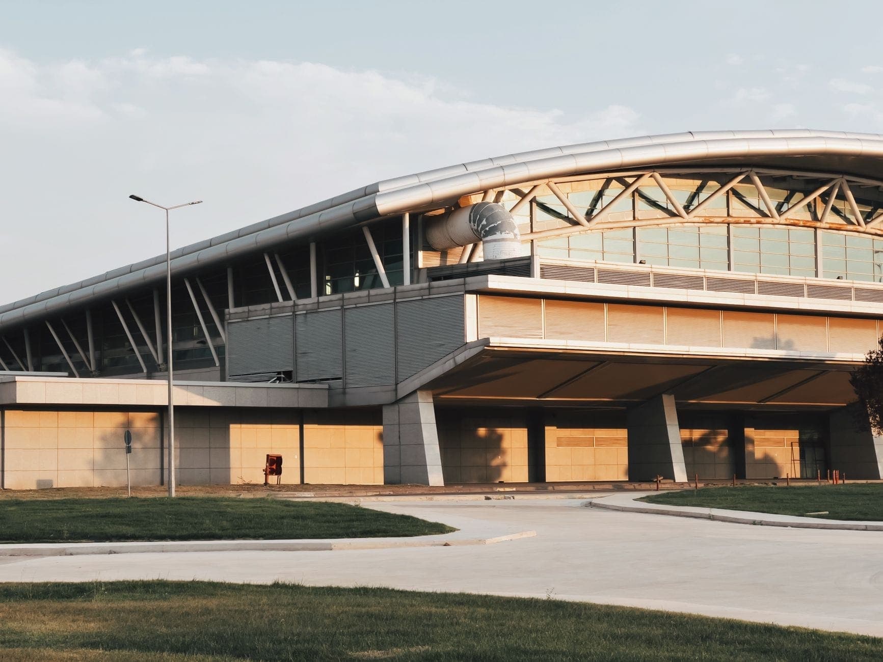 A modern airport terminal exterior with a curved roof, matching the Perth Airport T1 to T4 pickups Maxi Cab Perth covers. Maxi Cab Perth runs fixed-fare maxi taxi pickups in Belmont.