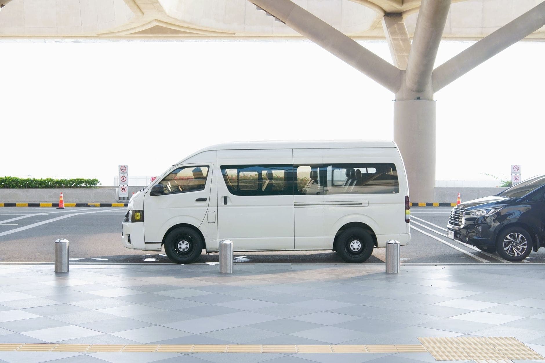 White high-roof Toyota Hiace maxi cab parked at an airport terminal drop-off zone, the vehicle type Maxi Cab Perth uses for group and airport transfers